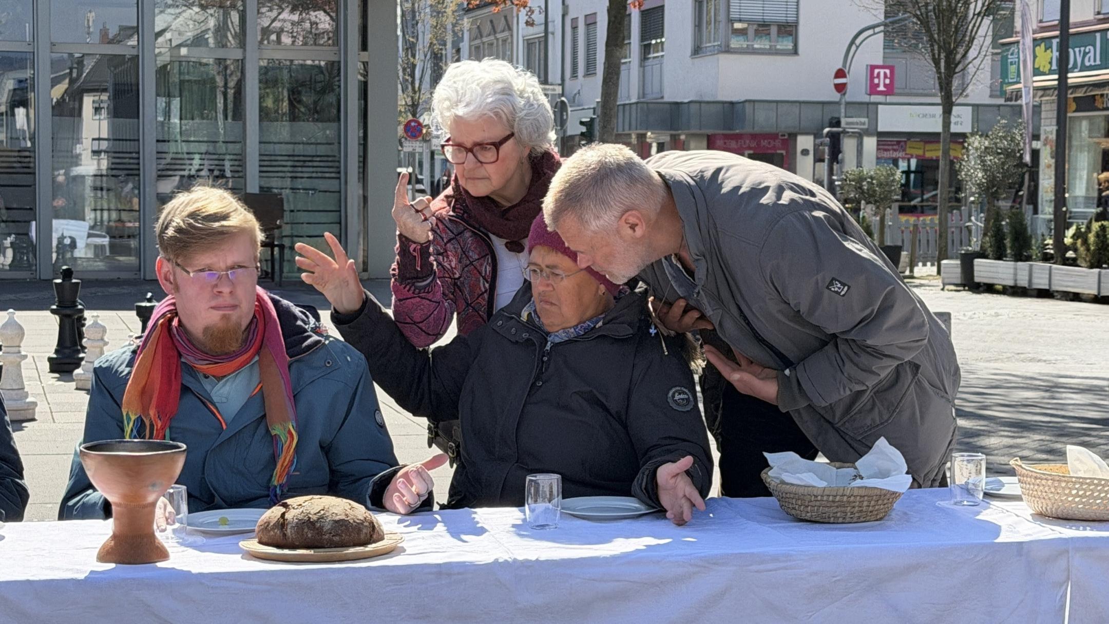 Der Jesus-Darsteller sitzt im Rollstuhl. Drei weitere Darsteller im fortgeschrittenen Alter beugen sich zu ihm.