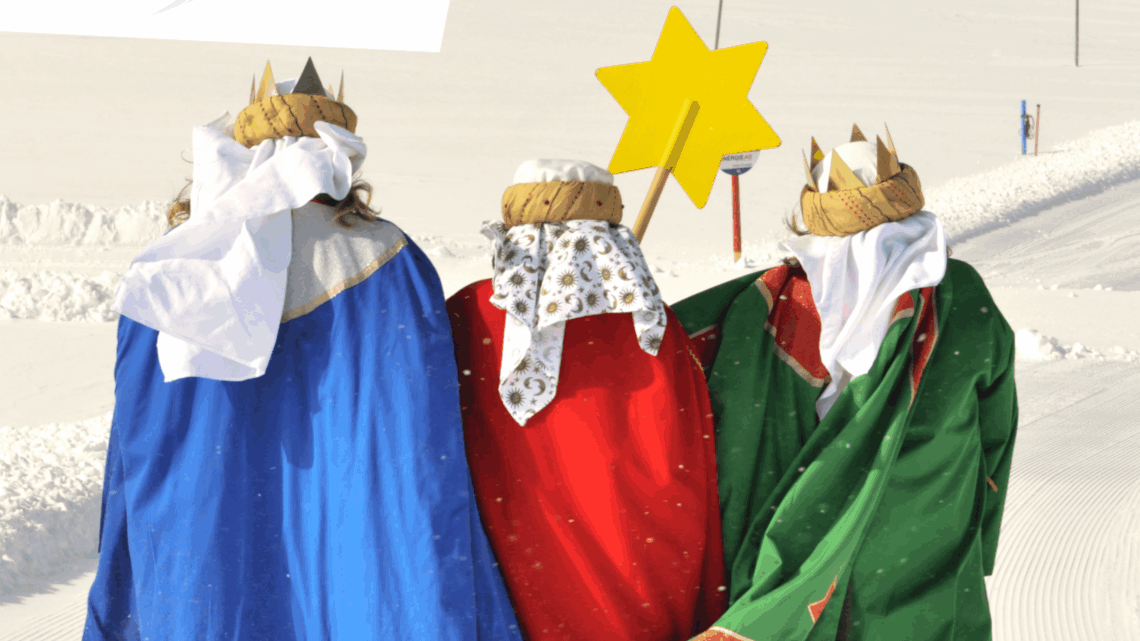 Drei Sternsinger*innen - von hinten zu sehen, in blauem, rotem und grünem Gewand - stapfen durch den Schnee.