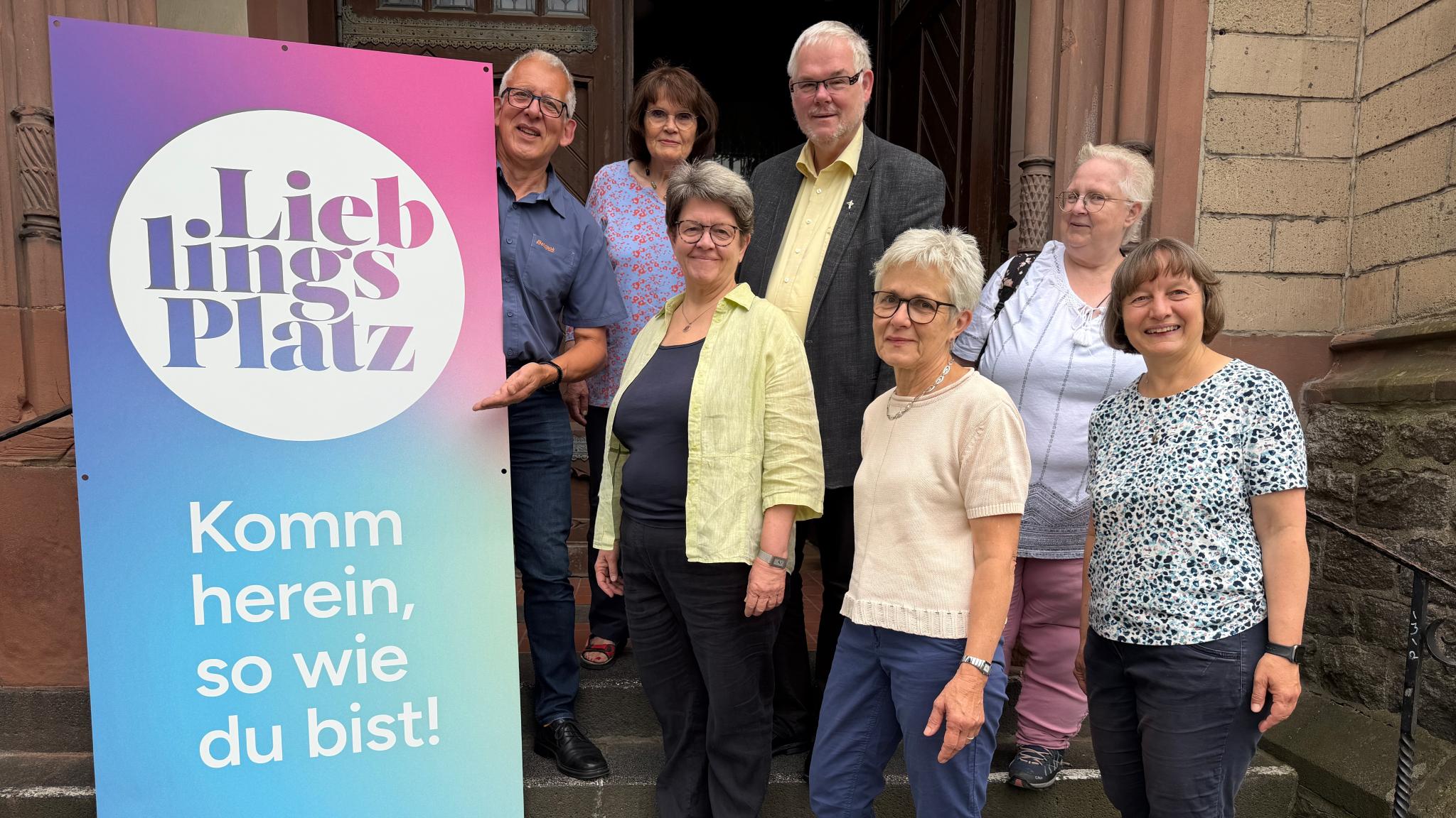Das Team des Projektes 'LieblingsPlatz' steht auf den Stufen zum Eingang der Pfarrkirche.
