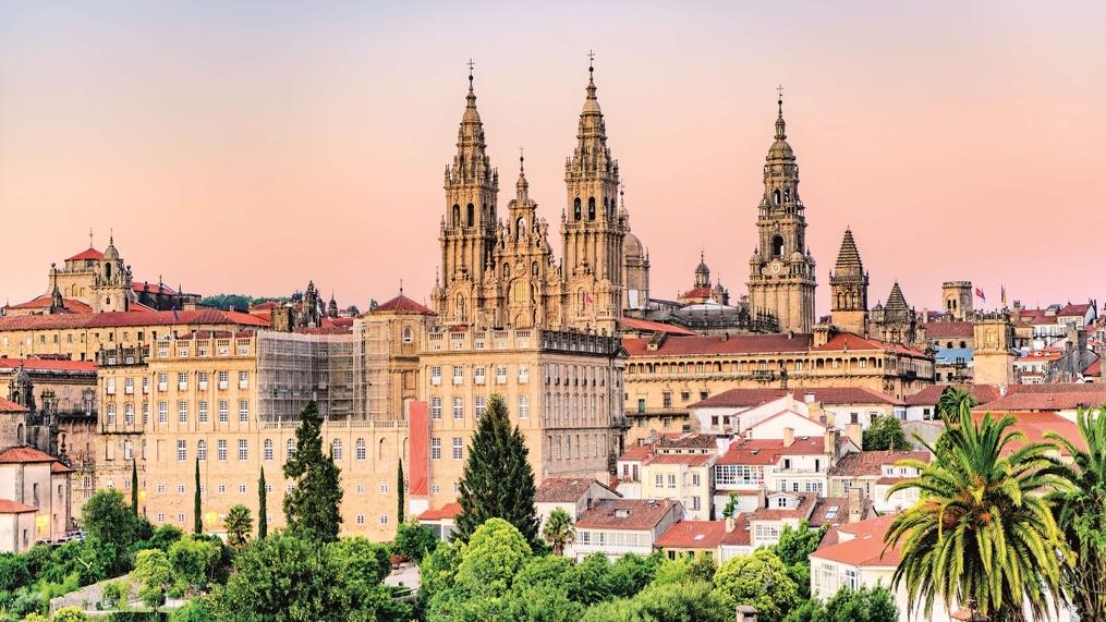 Am Abendlicht erscheint der Himmel über der Kathedrale in orange-rosa Farbtönen. Die Kathedrale liegt etwas versteckt hinter weiteren Gebäuden der Altstadt.